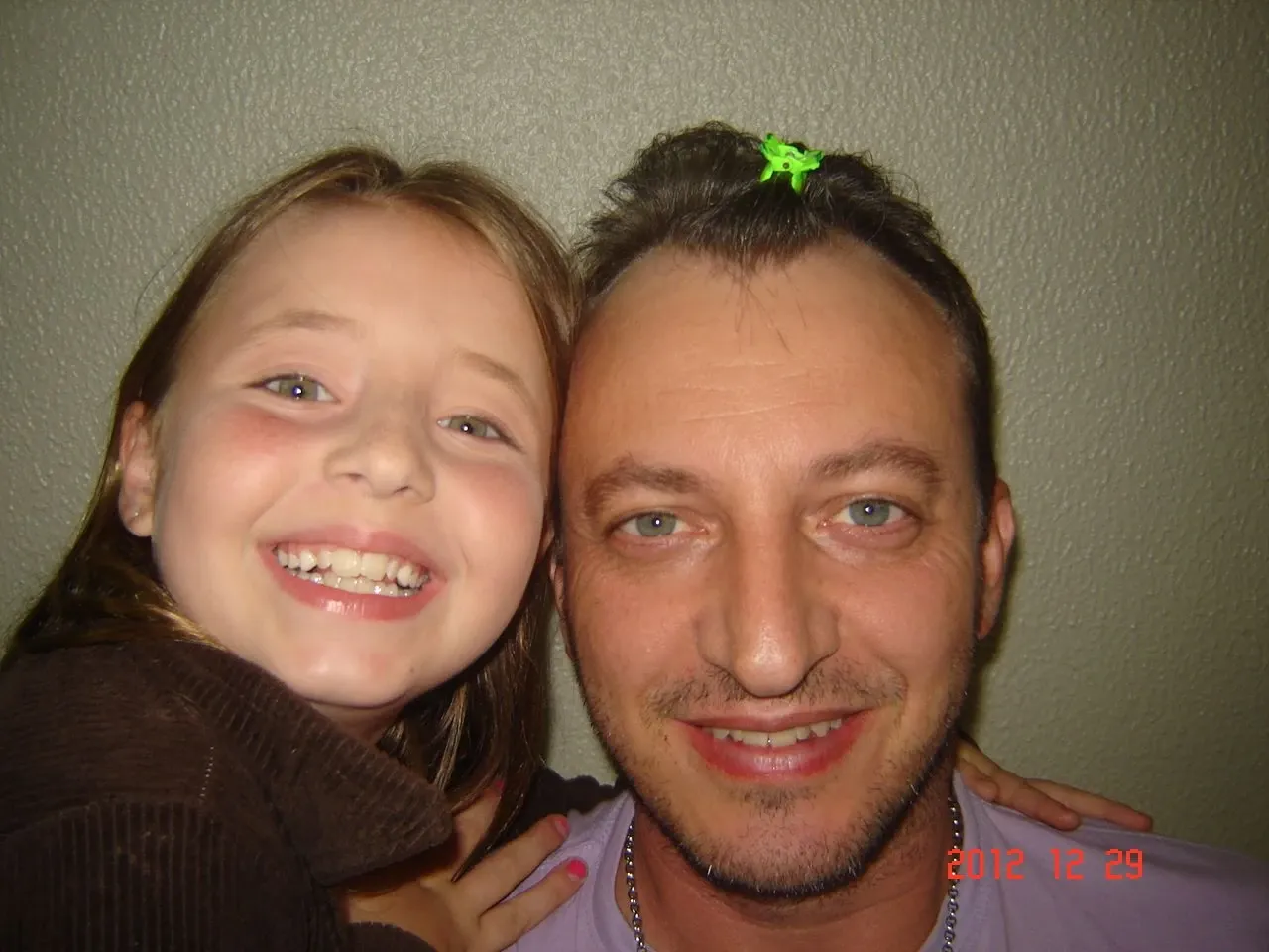 Pai e filha sorrindo para a câmera, com a filha na frente do pai.