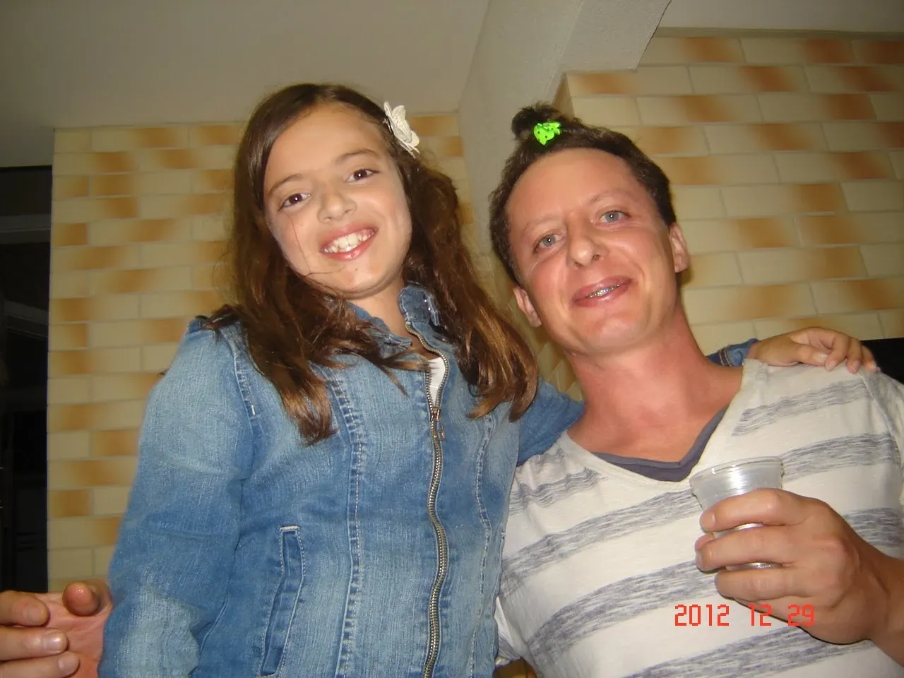 Um homem e uma menina sorrindo para a câmera, com o braço do homem em volta da menina.