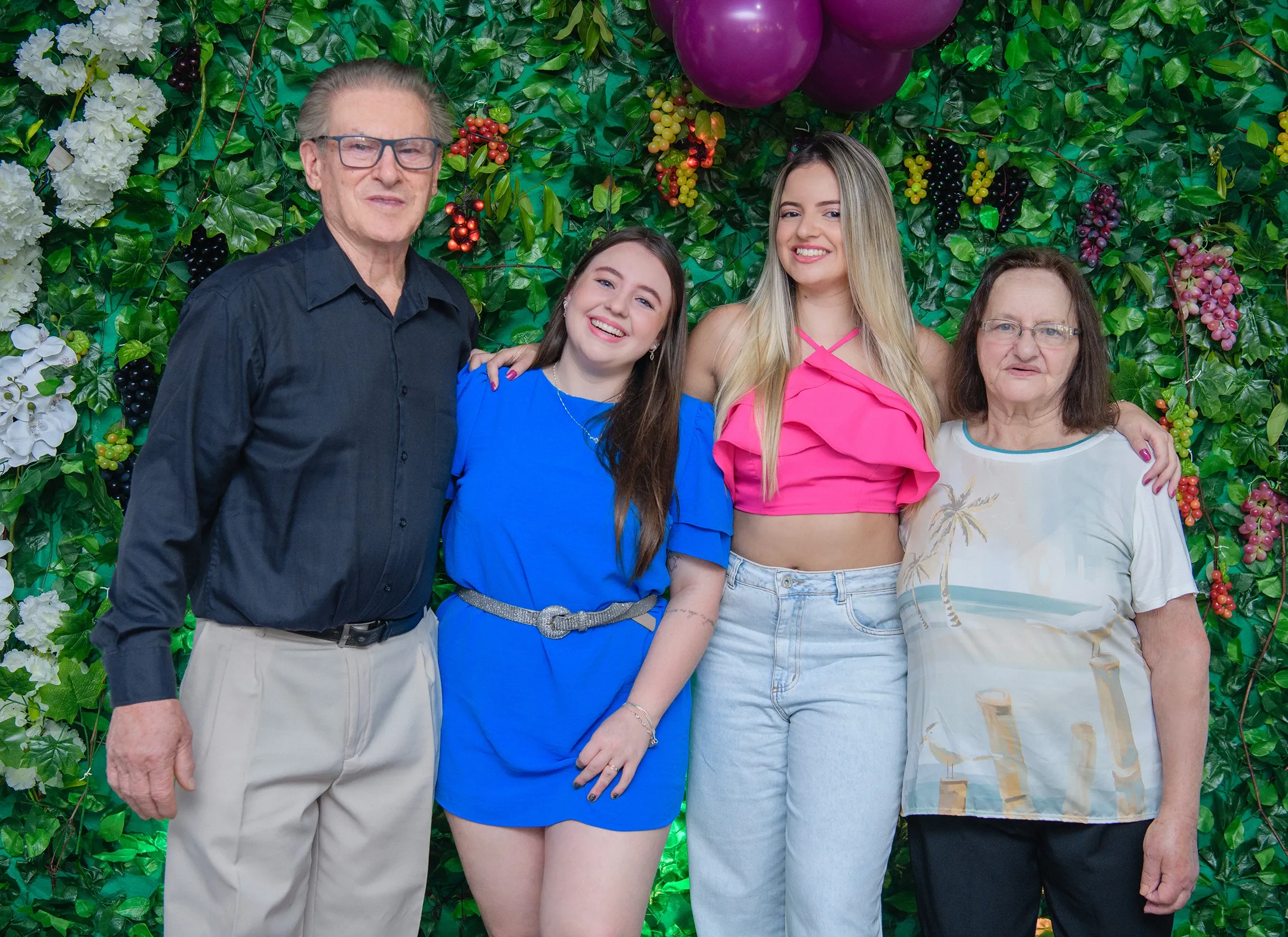 Um homem e três mulheres estão em frente a uma parede coberta de plantas e flores.