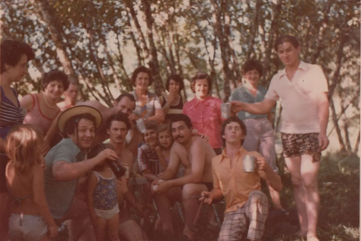 Um grupo de vinte pessoas de várias idades está posando para uma foto ao ar livre. (Original)