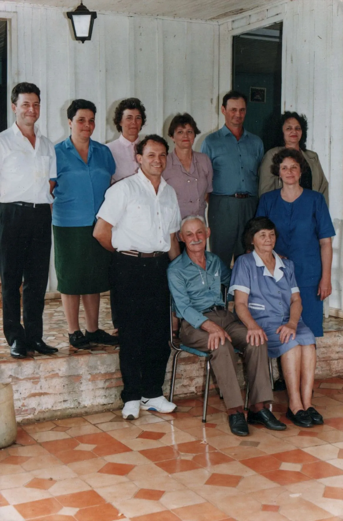 Um grupo de nove pessoas está posicionado na varanda de uma casa.