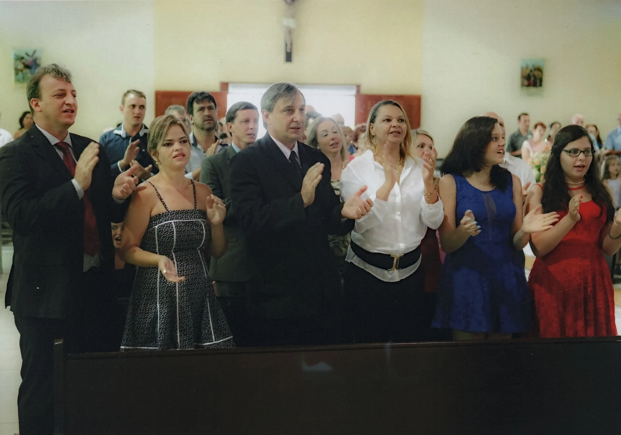 Pessoas em uma igreja aplaudindo, com a maioria delas olhando para frente.