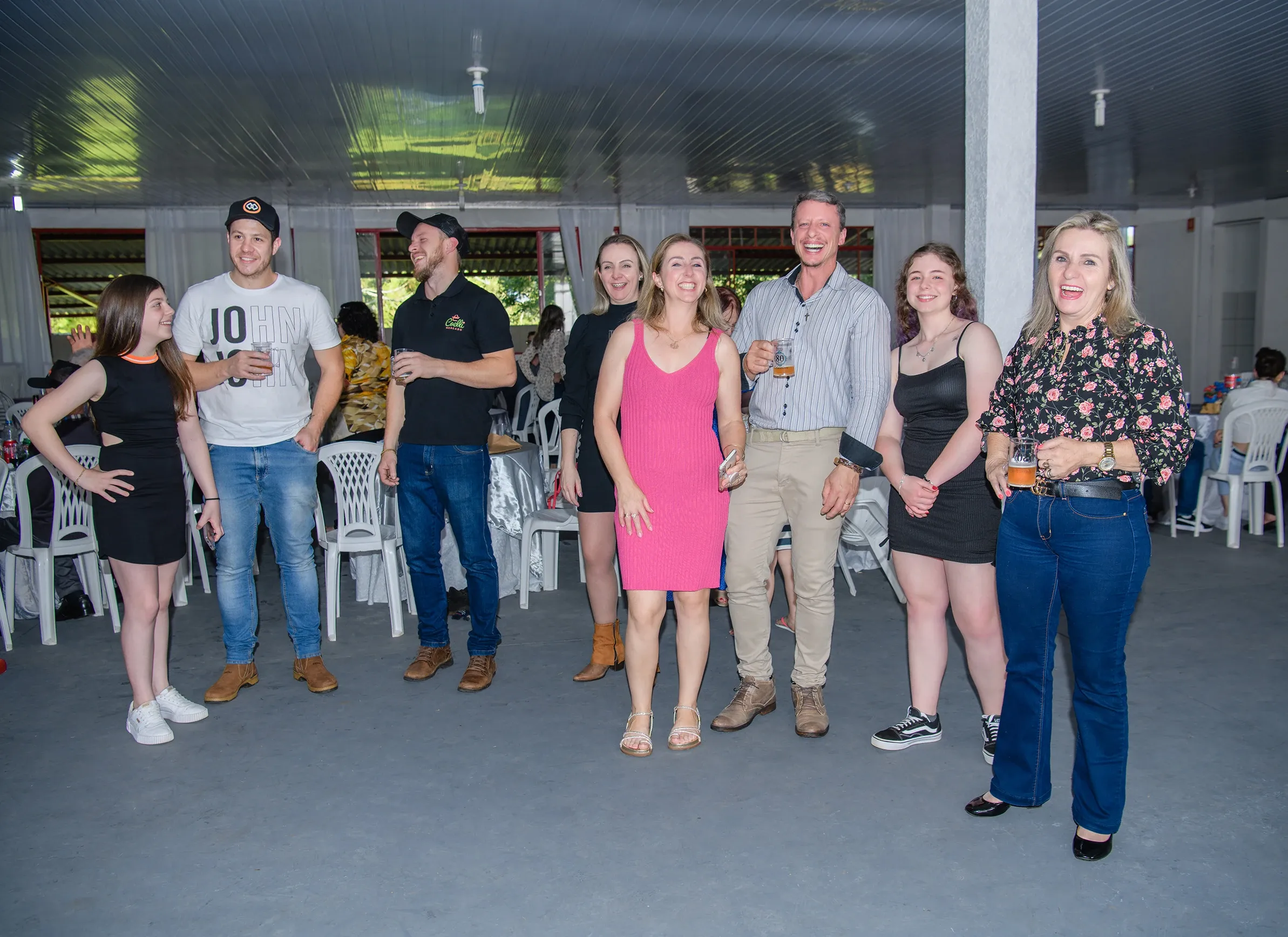 Um grupo de oito adultos e um adolescente posa e sorri em um evento interno.