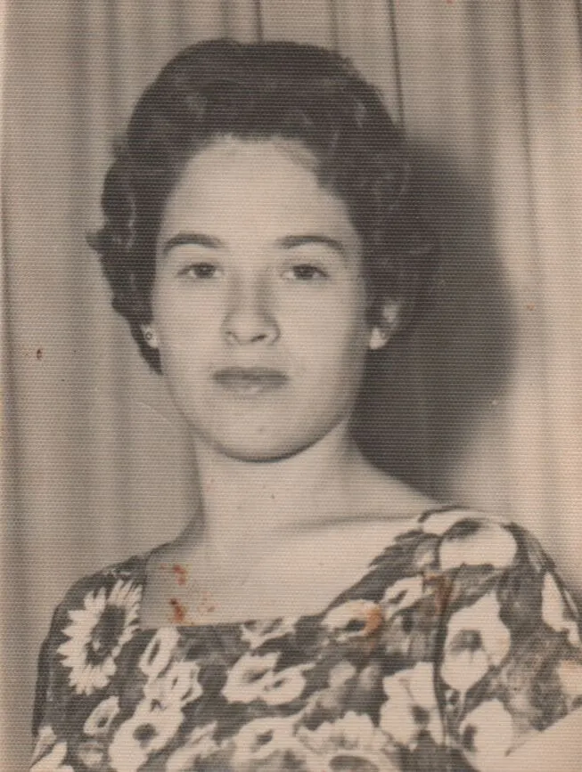 Retrato de uma jovem com cabelos escuros ondulados e lábios cor de cereja, usando um vestido floral. (Original)