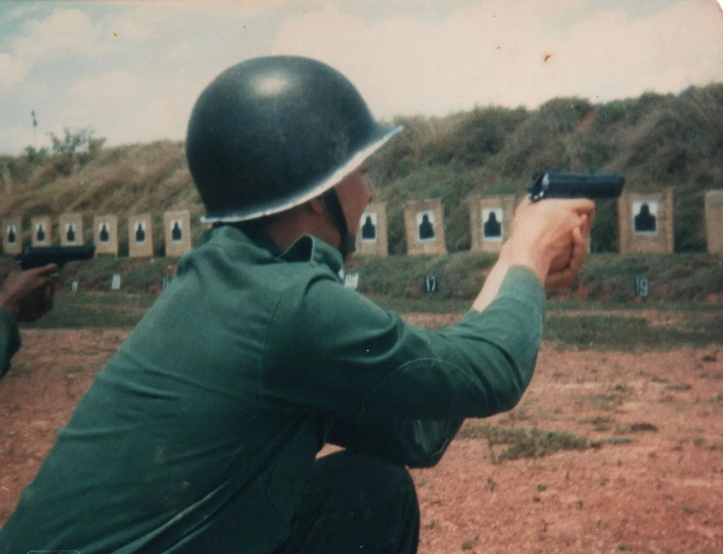 Um soldado atira com uma arma de fogo em um alvo em um campo de tiro. (Original)