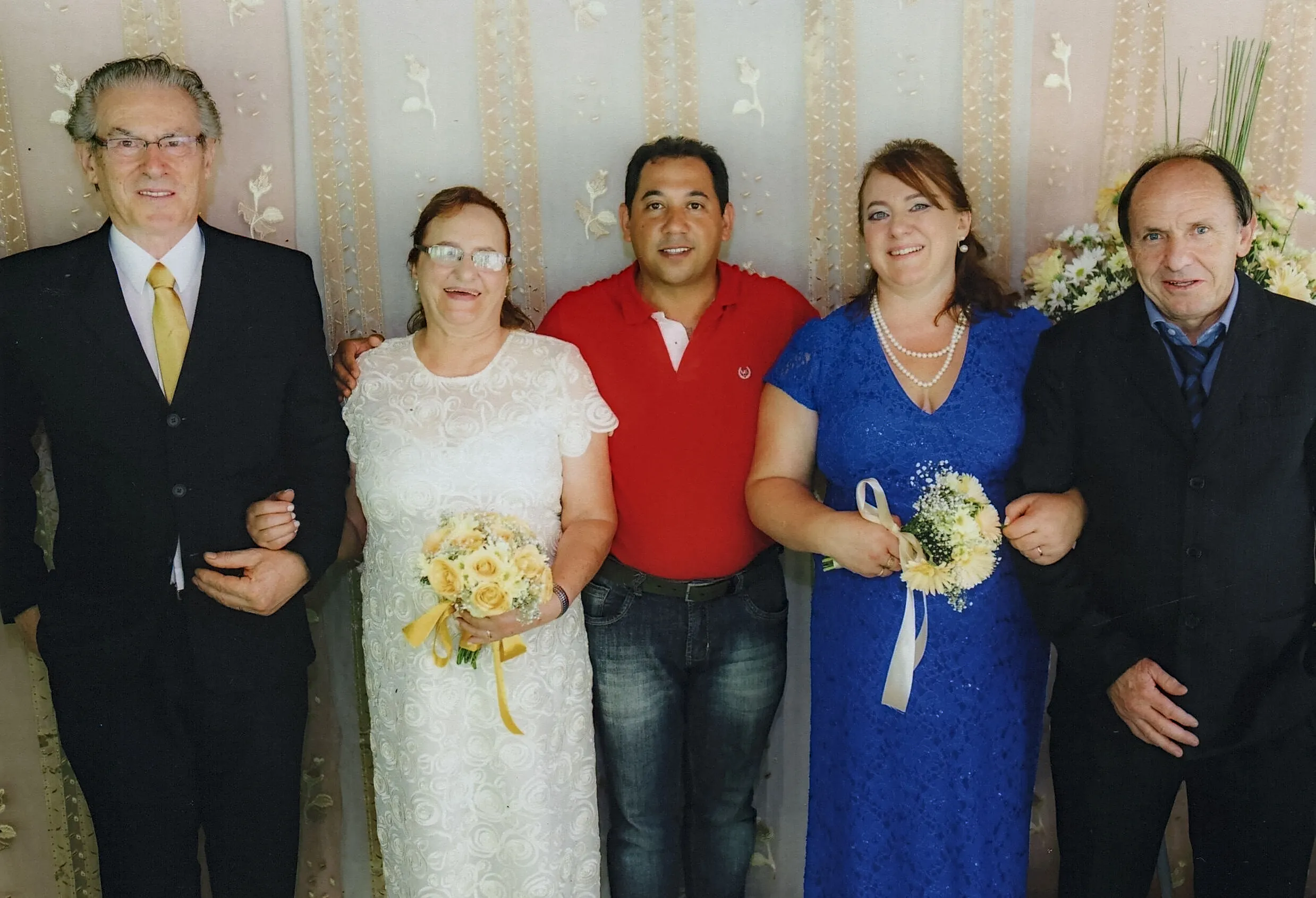 Cinco pessoas vestidas formalmente, sorrindo e posando para uma foto de família em um fundo creme.