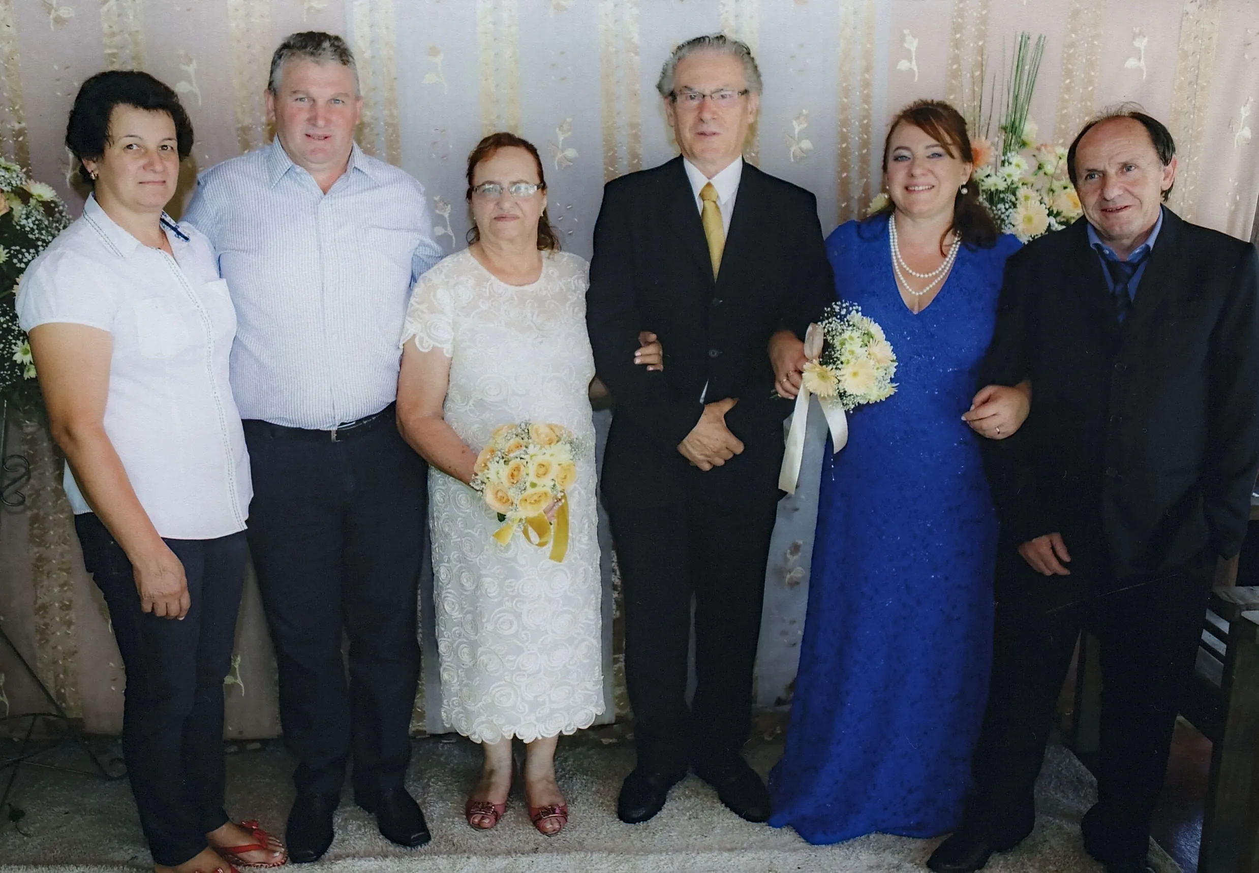 Seis adultos em trajes formais posando para uma foto de família em um casamento.