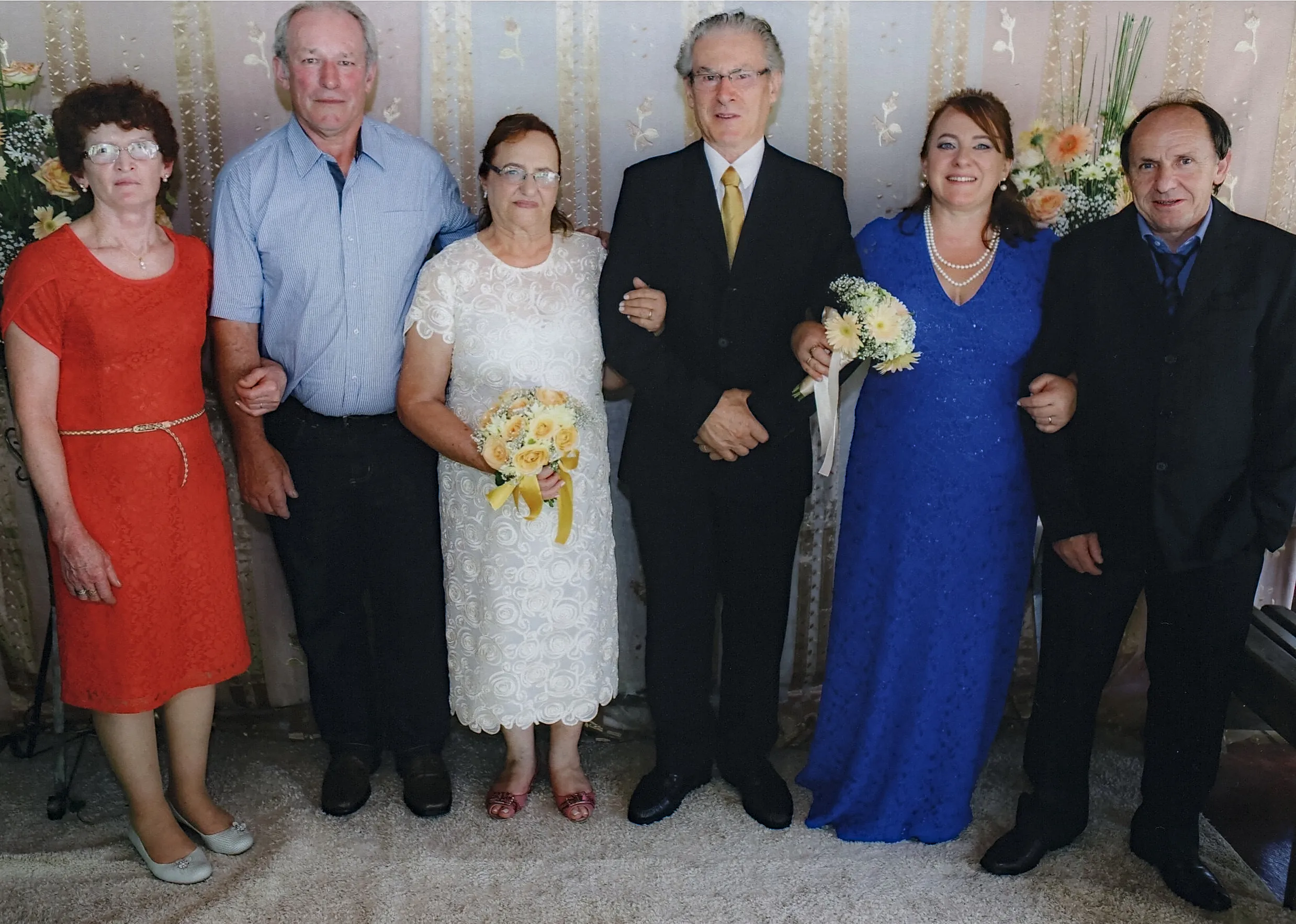 Seis pessoas de diferentes idades em trajes formais posam para uma foto em um casamento.