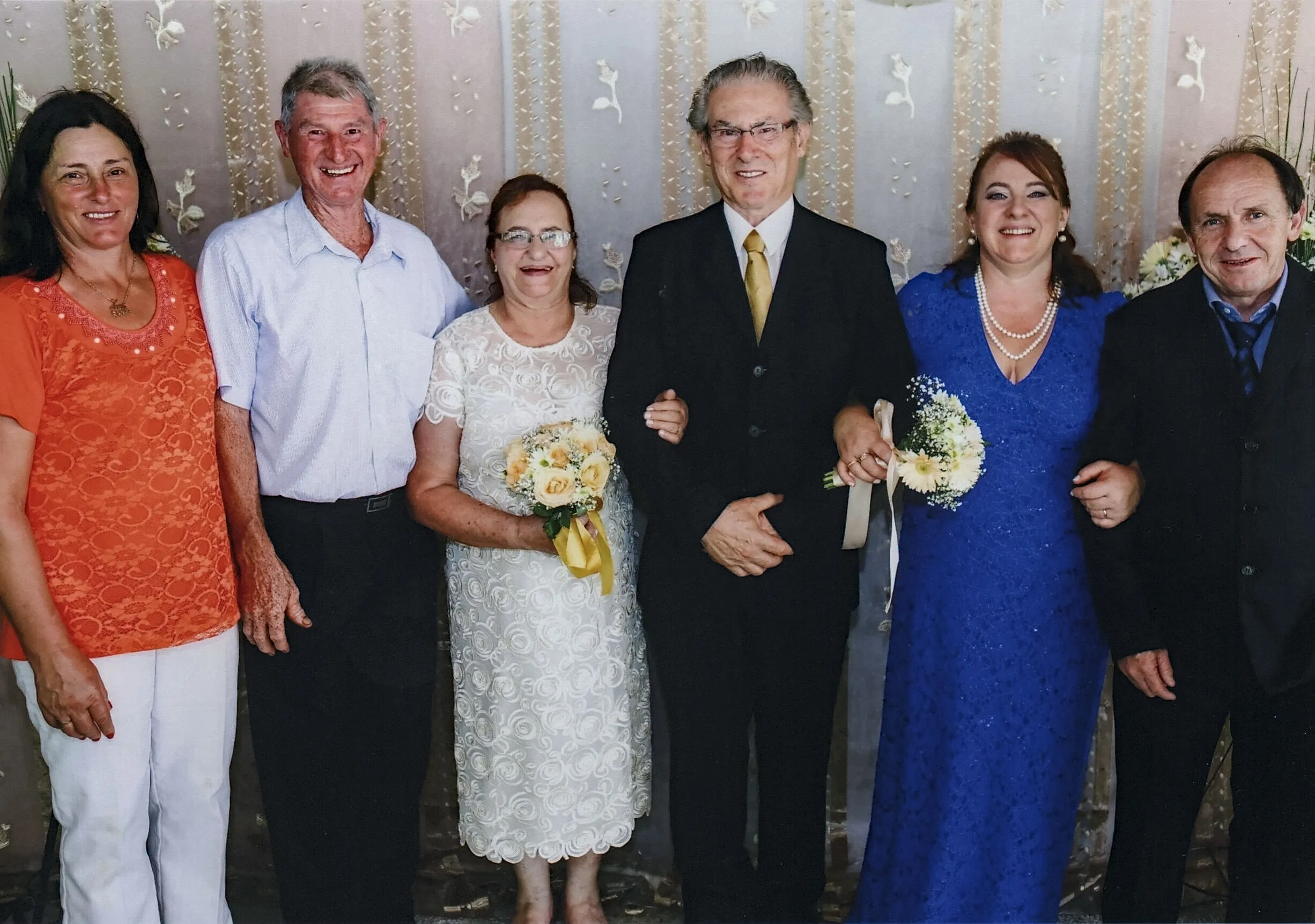 Seis pessoas em trajes formais posam para uma foto em um evento.