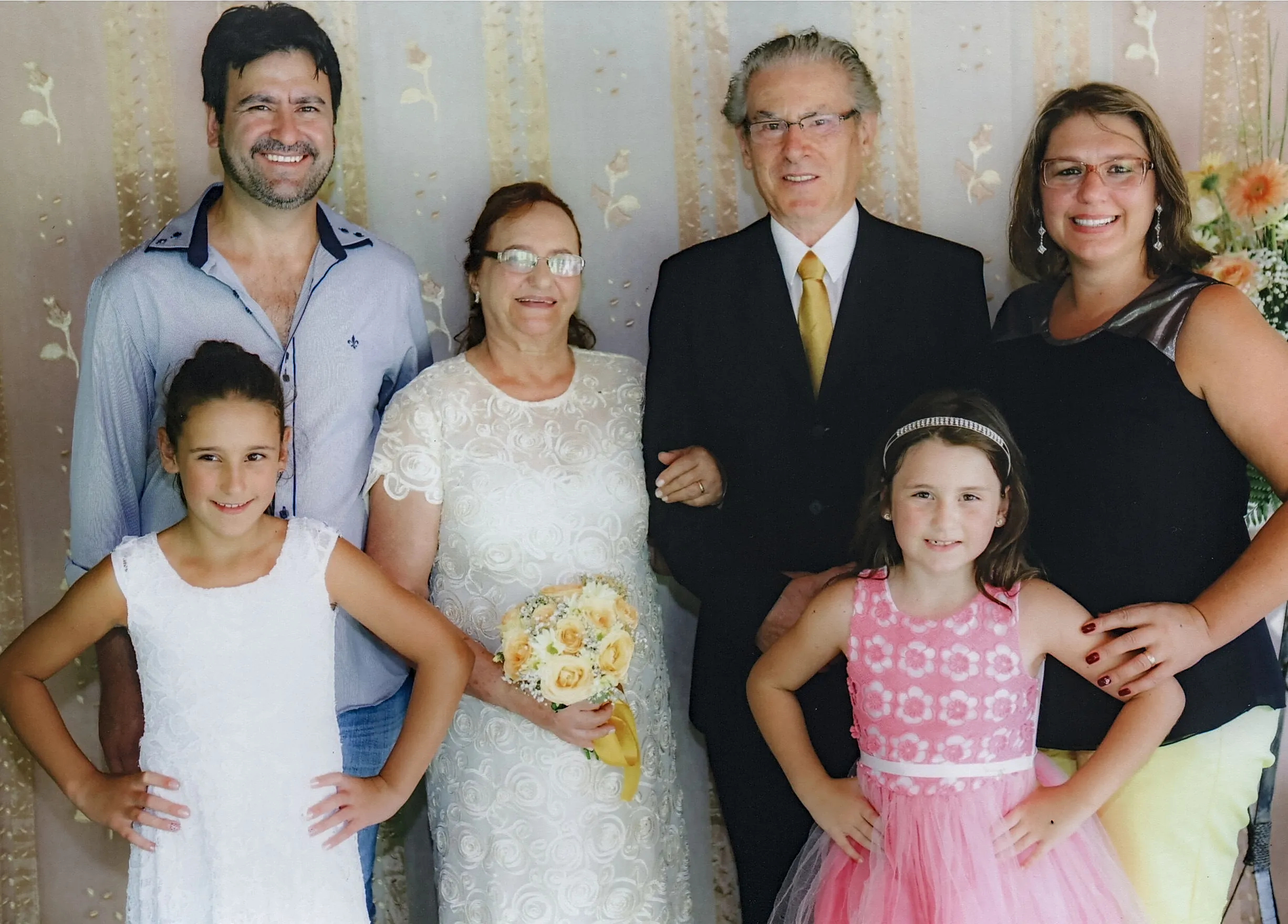 Um homem, uma mulher e duas meninas sorrindo posam para uma foto de família.